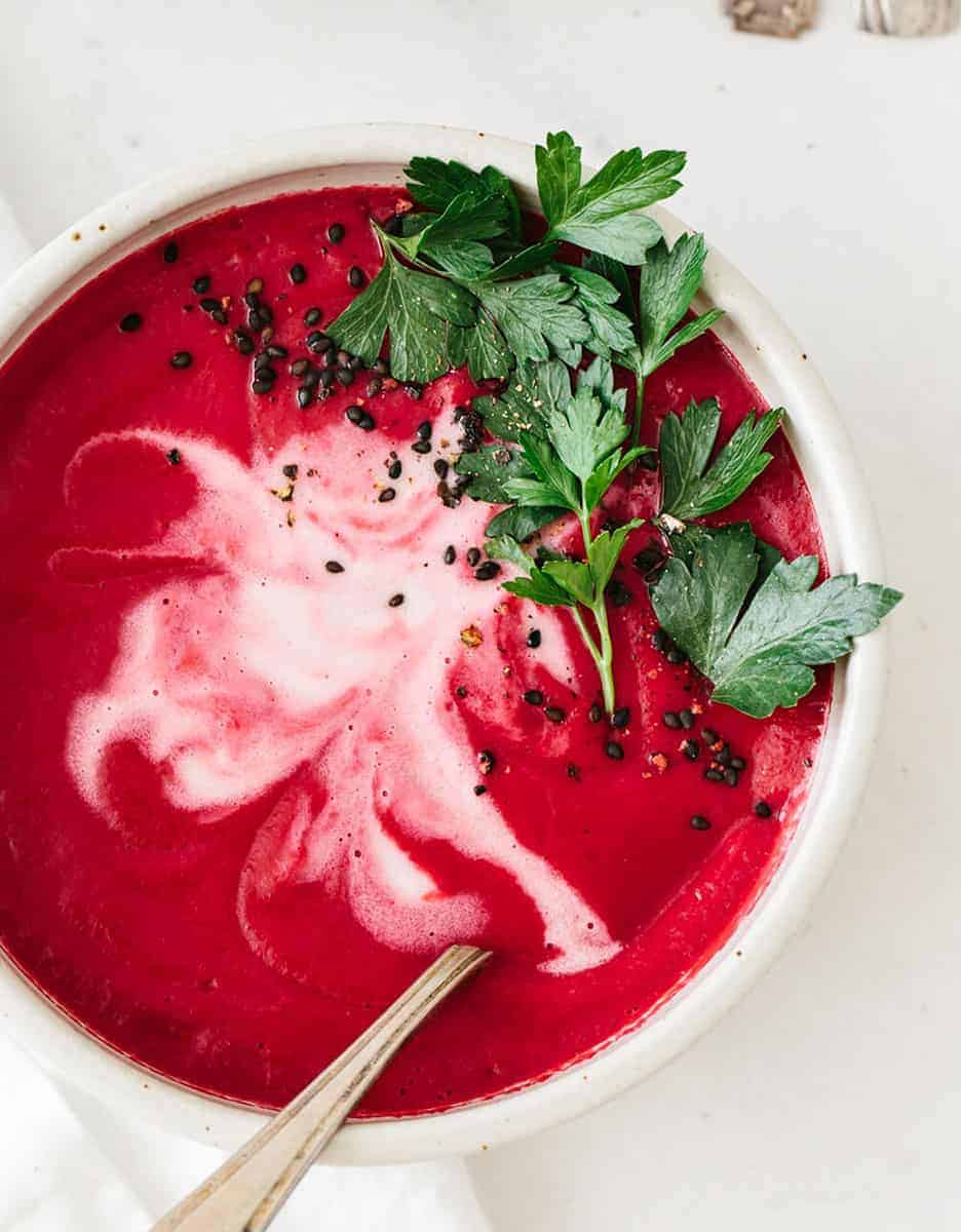 Low calorie beetroot soup with parsley leaves on a white background - Downshithology