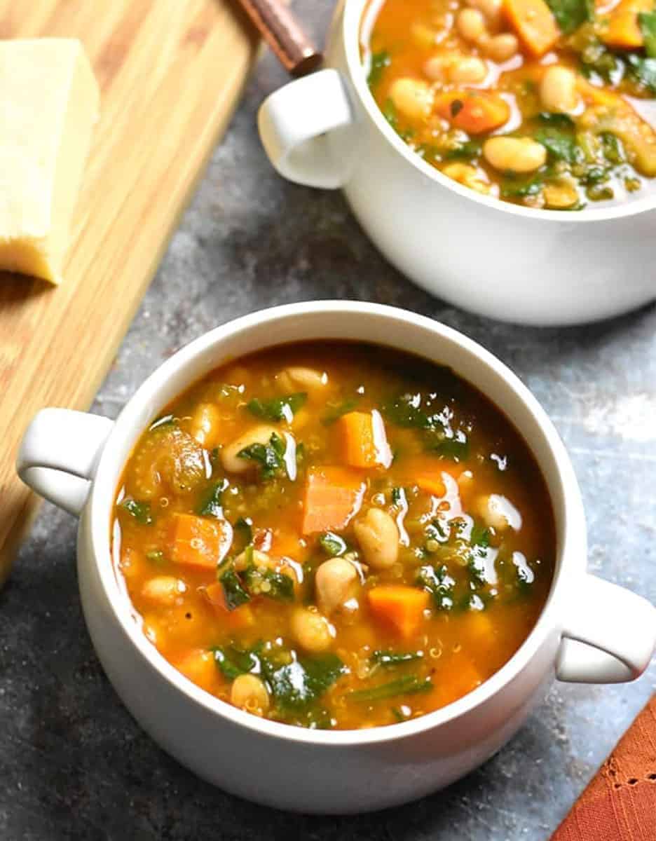 Minestrone soup in two white bowls on a grey background - Spice Cravings