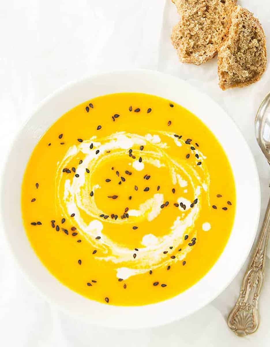 Low calorie carrot and ginger soup in a white bowl on a white background - The Clever Meal.