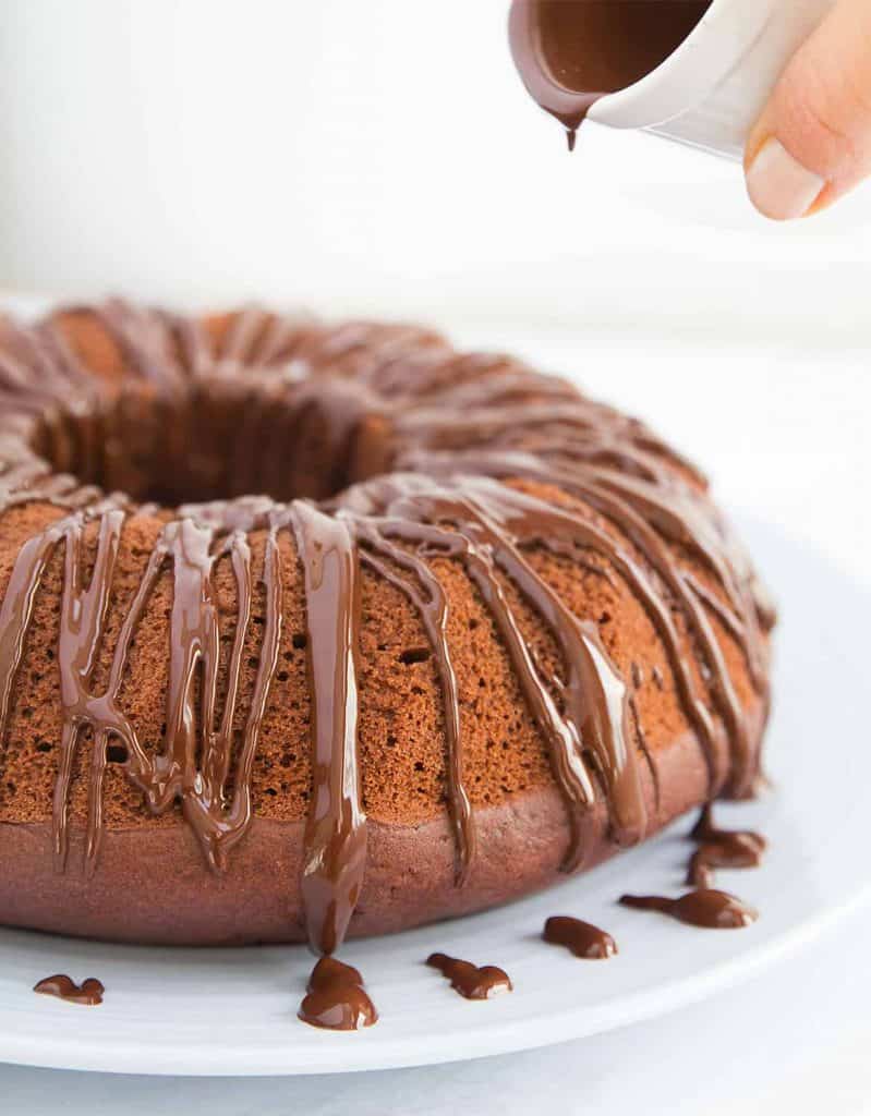 A little white just is pouring melted chocolate on the beetroot chocolate cake.