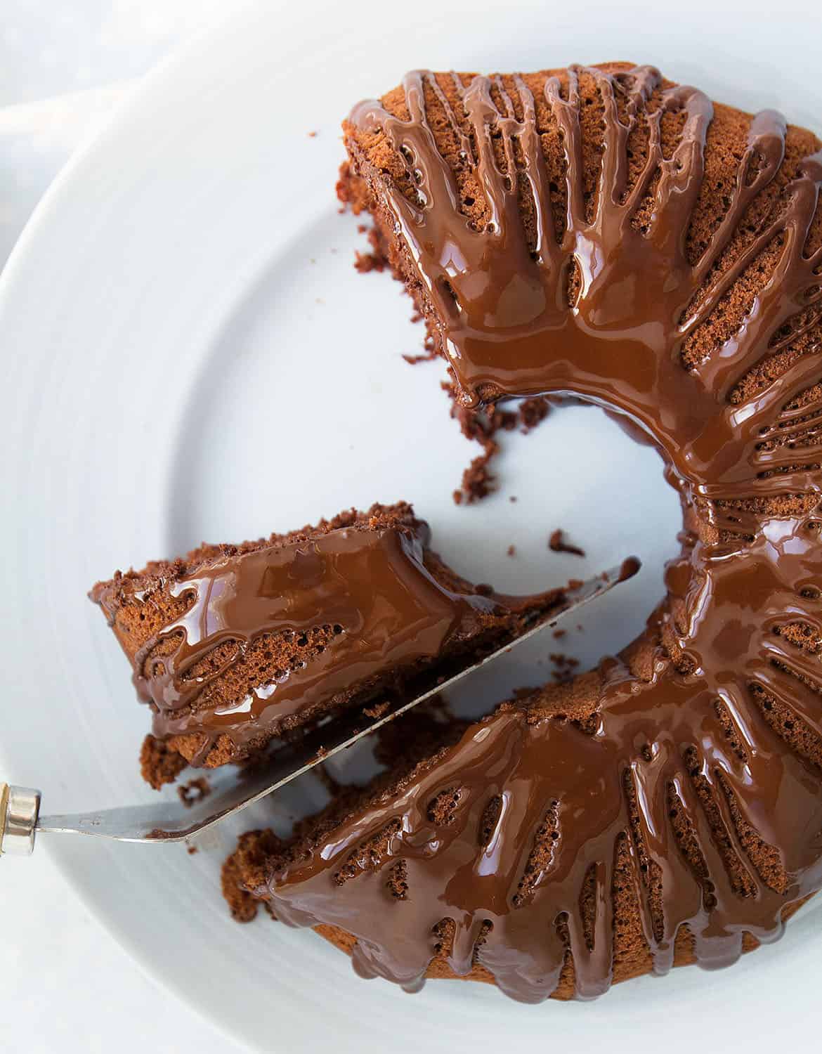 A knife is cutting a chocolate and beetroot cake on a light blue plate.