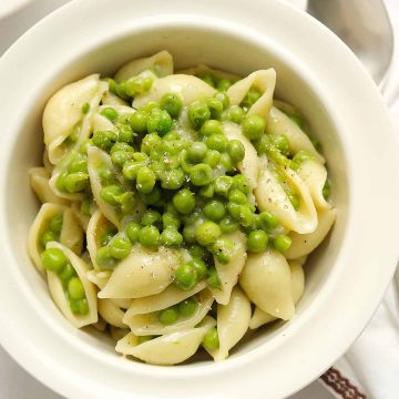 Pasta with peas in a white bowl.