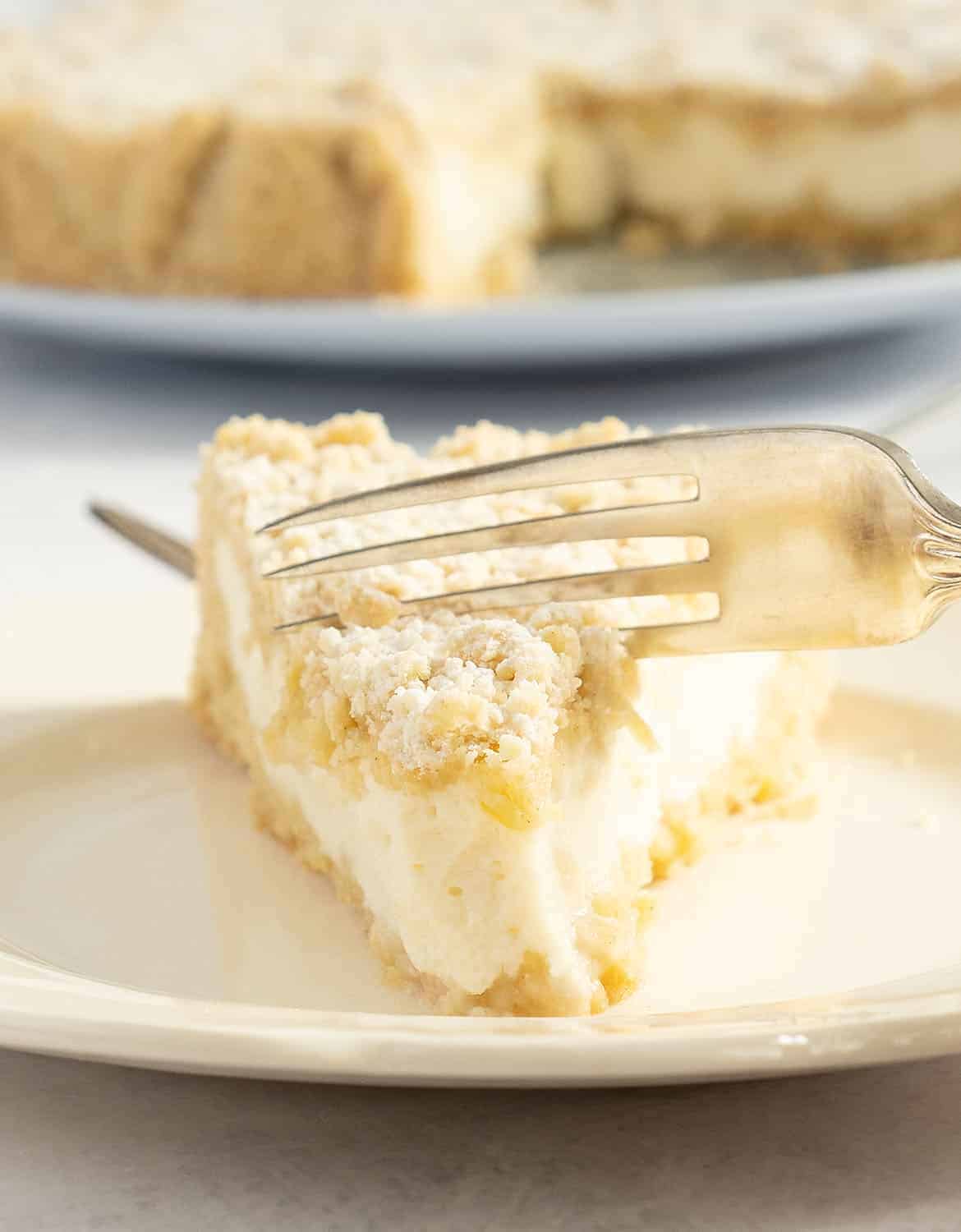 A fork and a slice of lemon ricotta cake on a small white plate.