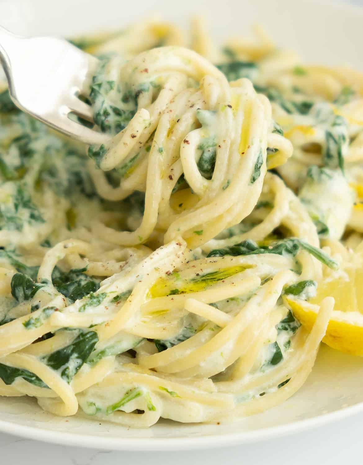 A fork is lifting some creamy lemon ricotta pasta noodles.