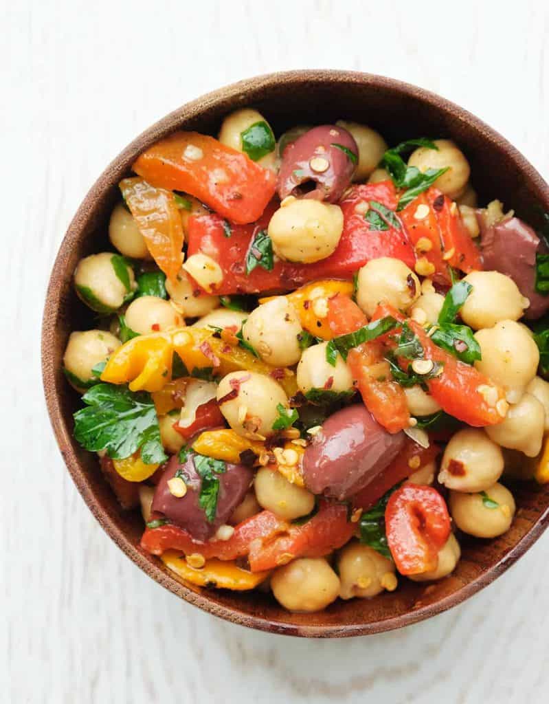 Spicy chickpea salad in a wooden bowl over a white background.