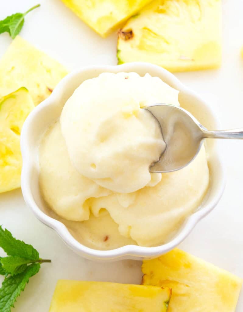 A spoon digging into some creamy and fresh pineapple sorbet.