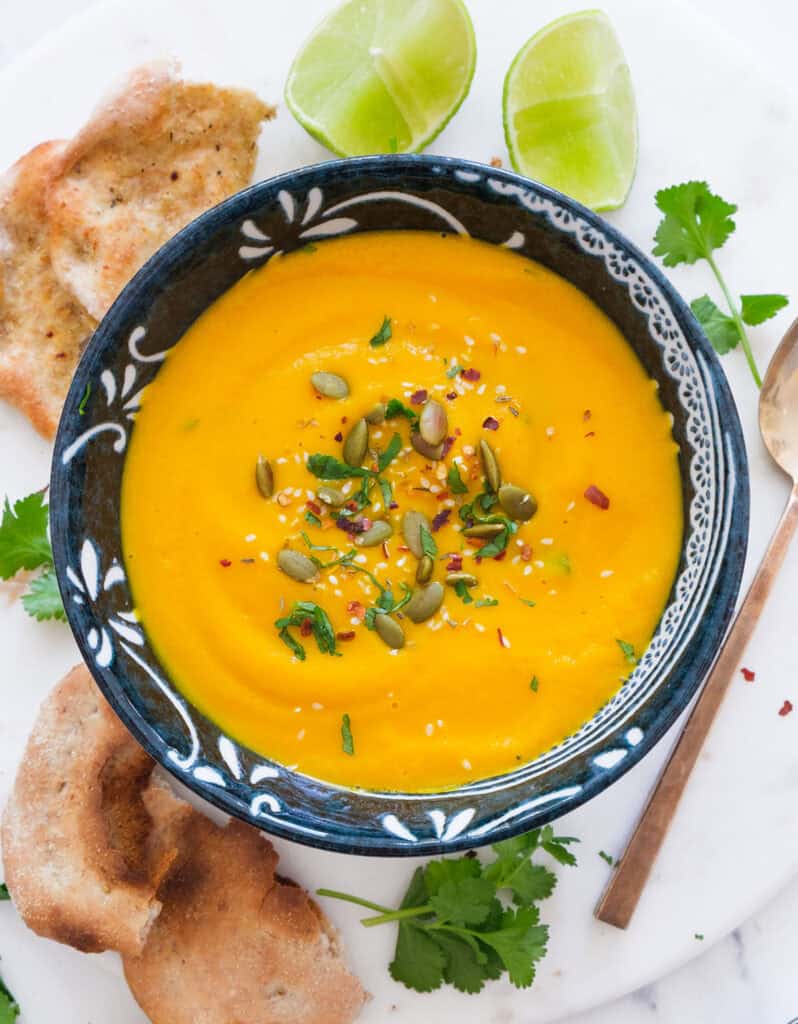 Top vie of a blue bowl full of carrot ginger soup.