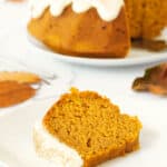 A slice of pumpkin bundt cake with cream cheese frosting on a white plate.