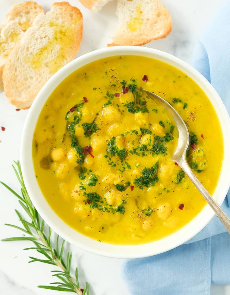 Top view of a bowl of butternut squash and chickpea soup with a spoon.