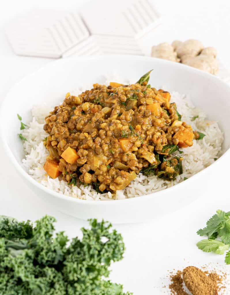 A white bowl full of rice and green lentil curry over a white background.