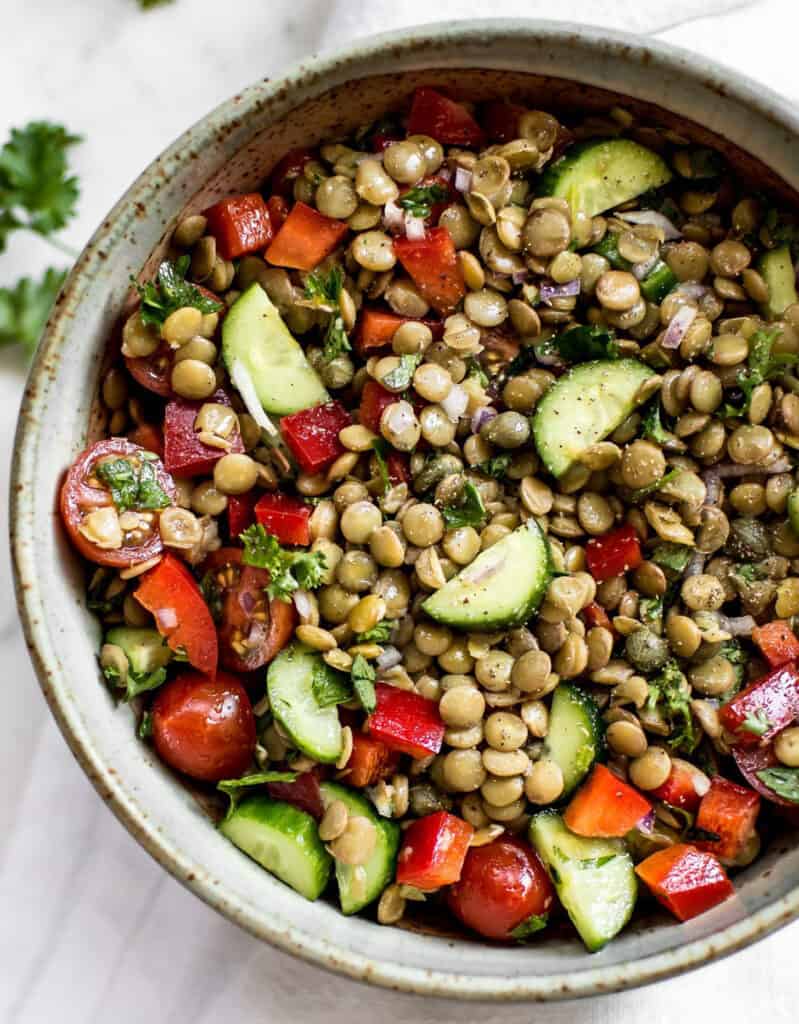 Top view of a green lentil salad with cucumber slices and tomatoes 