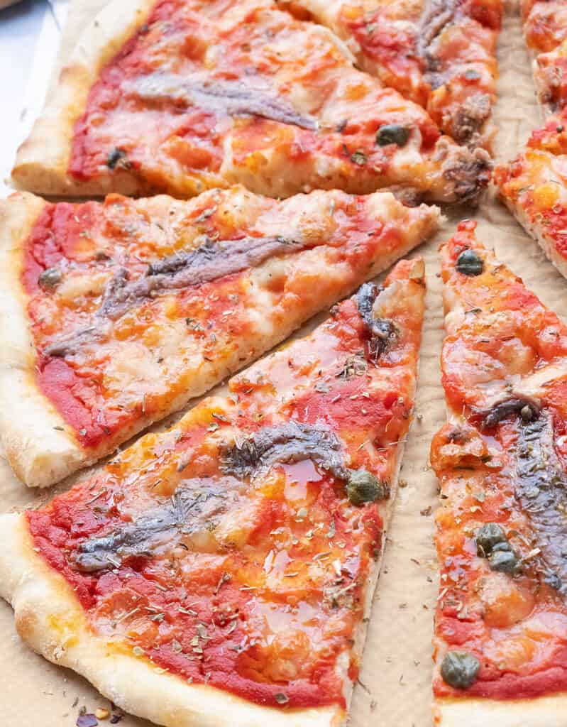 Close-up of large anchovy pizza cut into slices.