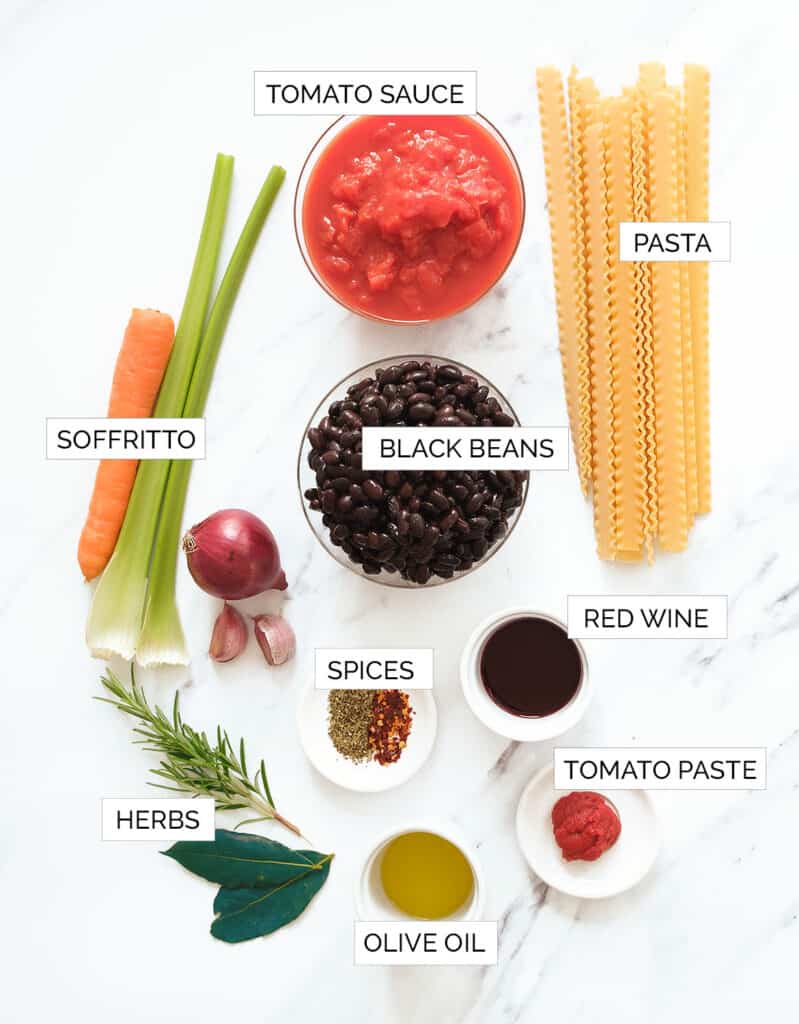 The ingredients for this pasta with black bean recipe are arranged over a white background.