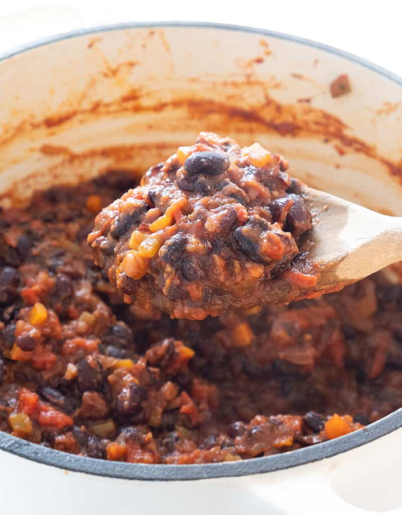 Close-up of a wooden spoon full of black bean sauce.