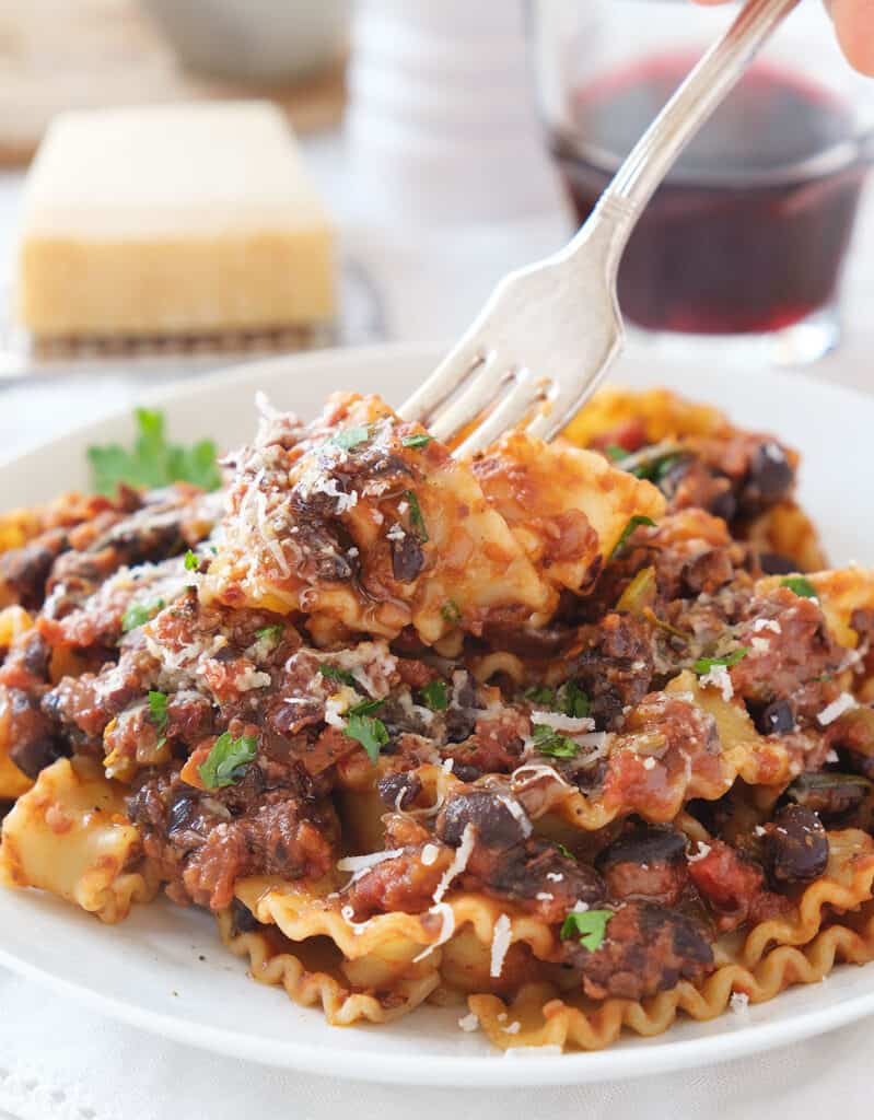 Close-up of a white dish with pasta with black beans.