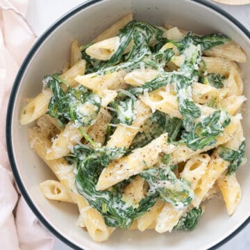 Top view of a bowl full of pasta with spinach.