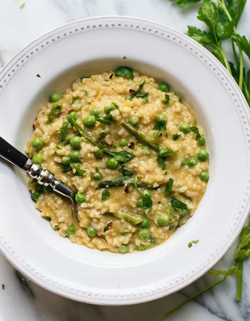 Top view of a white plate with asparagus and pea risotto.