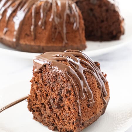 Close-up of a slice of easy chocolate cake with melted chocolate over a white background.