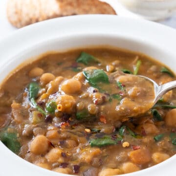 Close-up of a white bowl full of smoky chickpea and lentil soup.