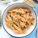 Top view of a bowl full of one-pot penne pasta with tomato sauce, basil and ricotta.