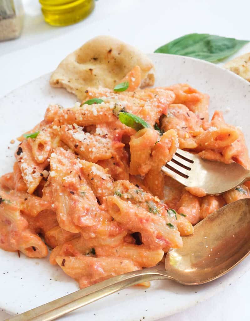 Close-up of a serving of tomato and ricotta pasta on a white plate.