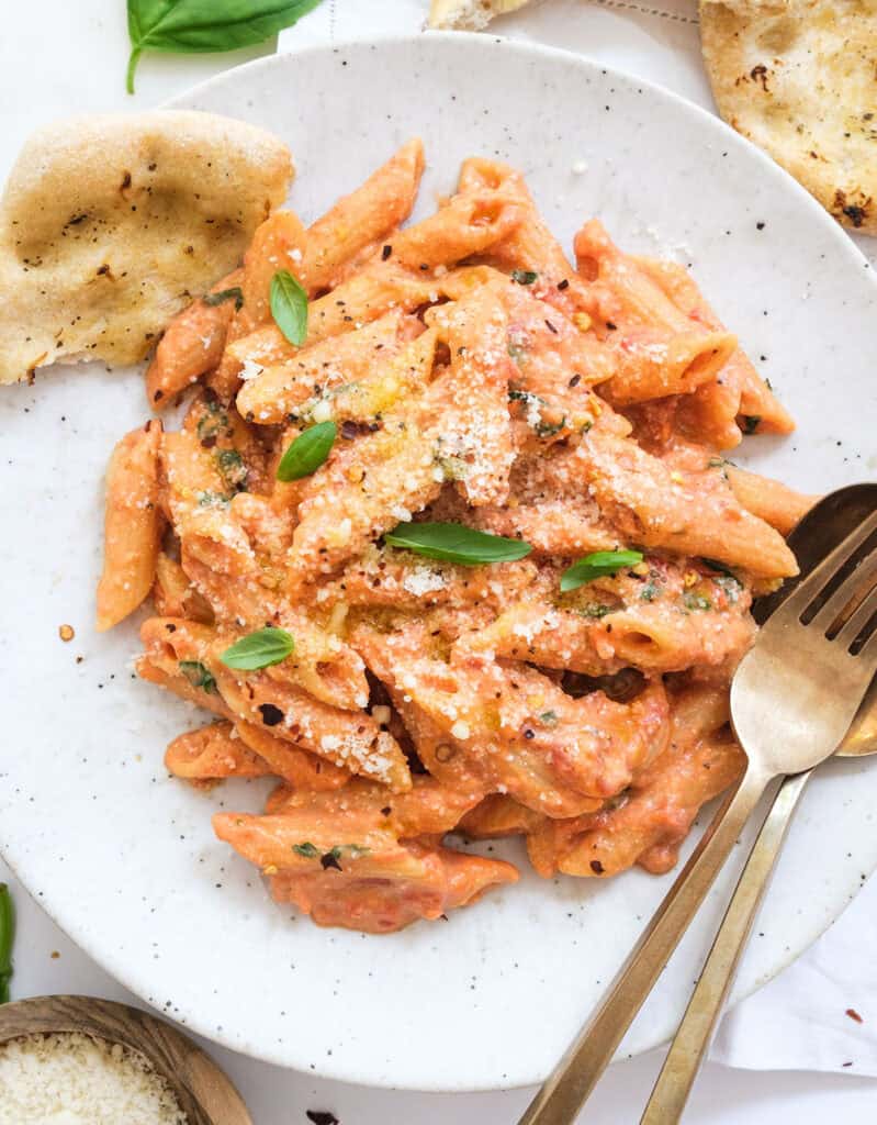 Tomato and ricotta pasta with basil on a white plate.