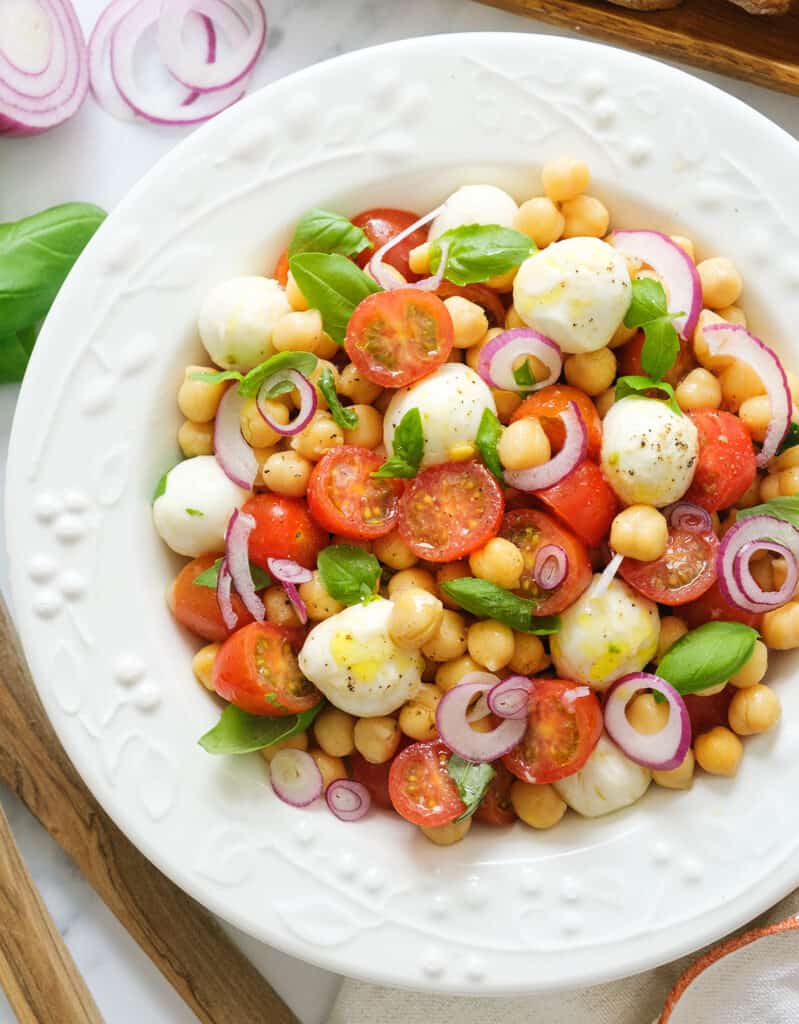 Top view of a white plate full of chickpea salad with cherry tomatoes and mozzarella pearls, one of my favorite chickpea recipes.