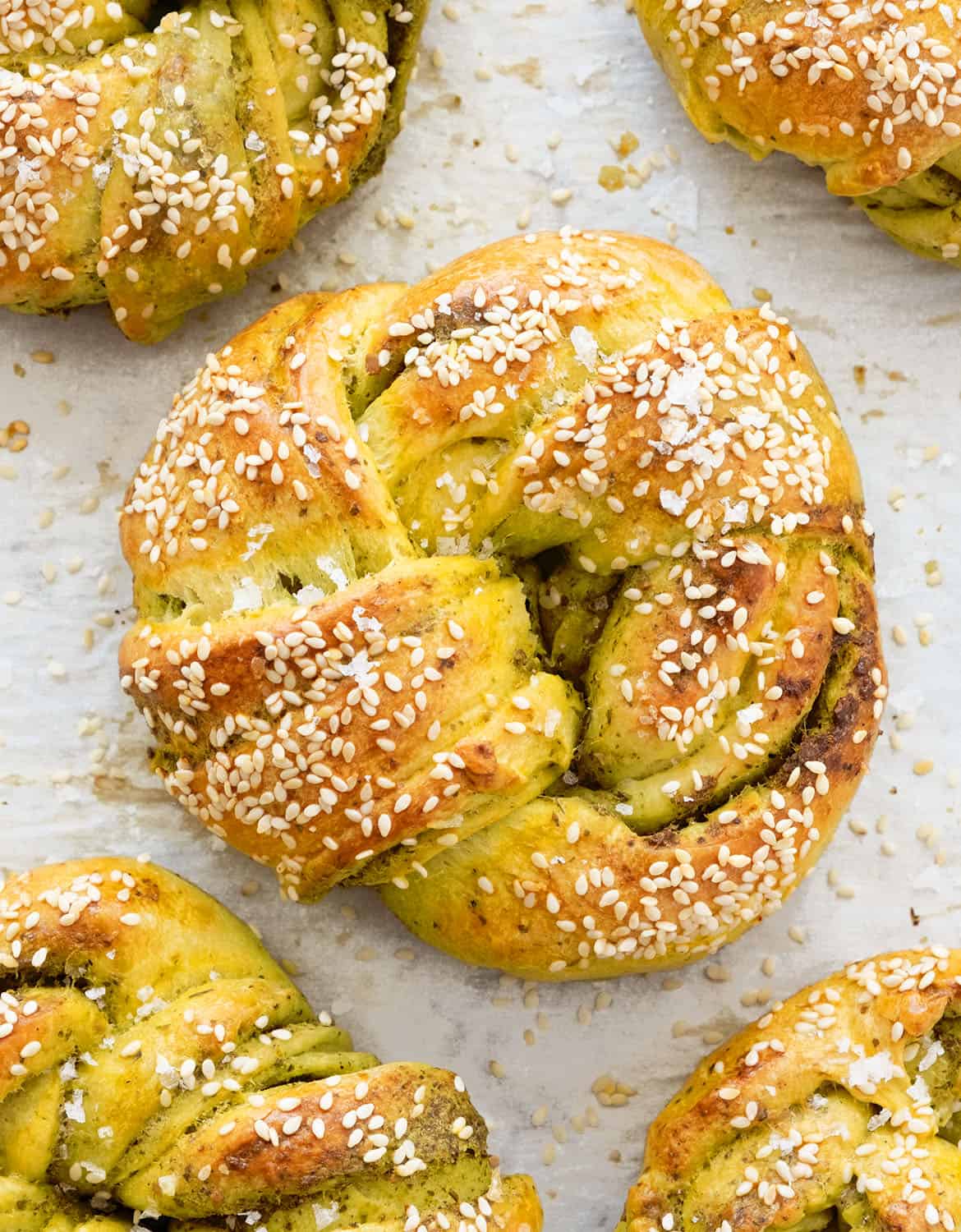 Top view of a large garlic bread knot 
with sesame seeds over white parchment paper.