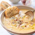 Close-up of a bowl full of garlic chickpea soup with crusty bread.