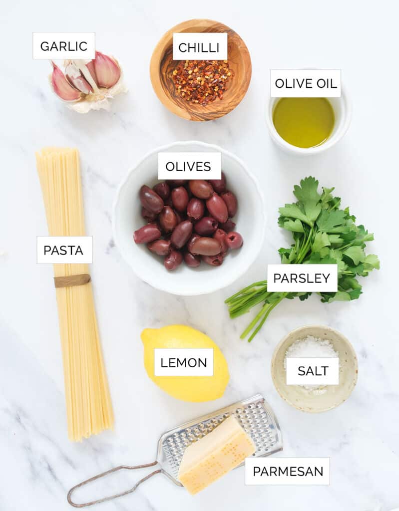 The ingredients to make this easy pasta with olives are arranged over a white background.