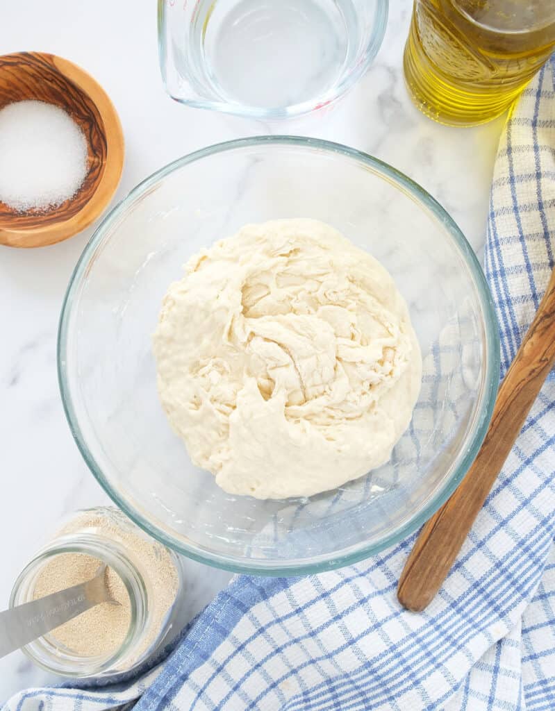 Top view of a glass bowl full of easy no-knead pizza dough.