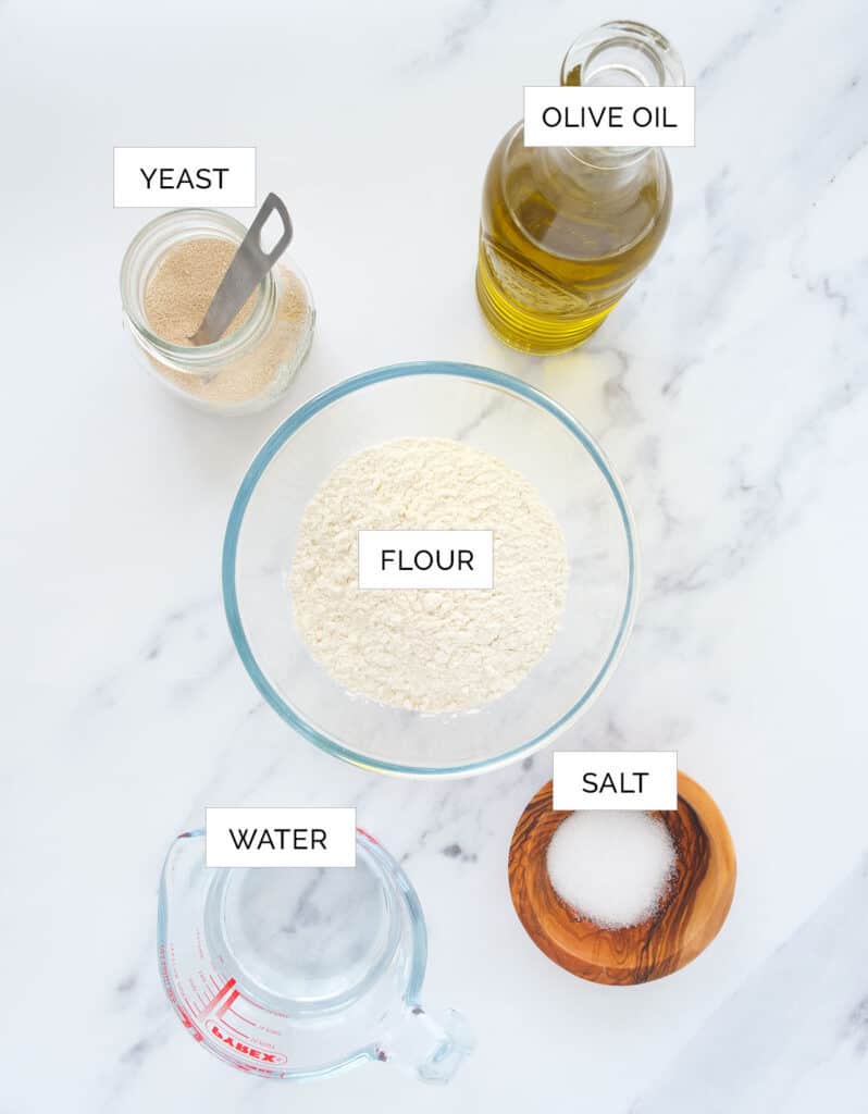 The ingredients to make this easu no-knead pizza dough are arranged over a white background.