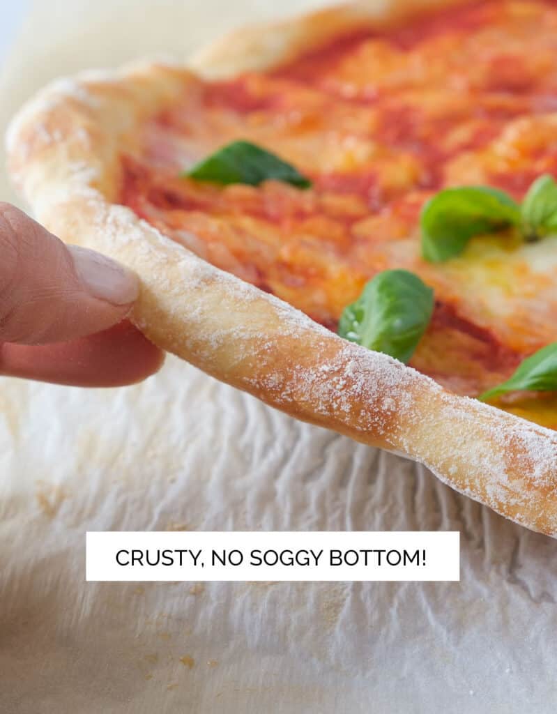 A hand lifting the pizza crust to show the crusty bottom.