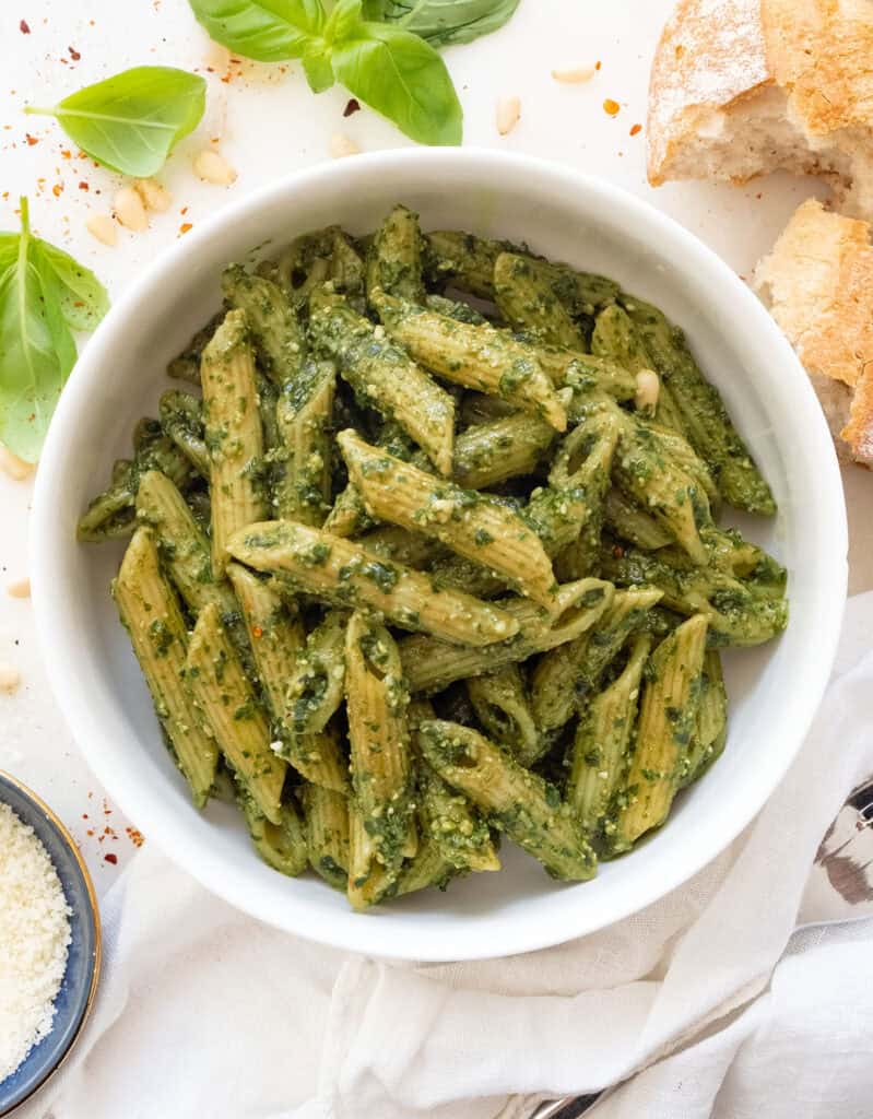 A white bowl full of penne with pesto.