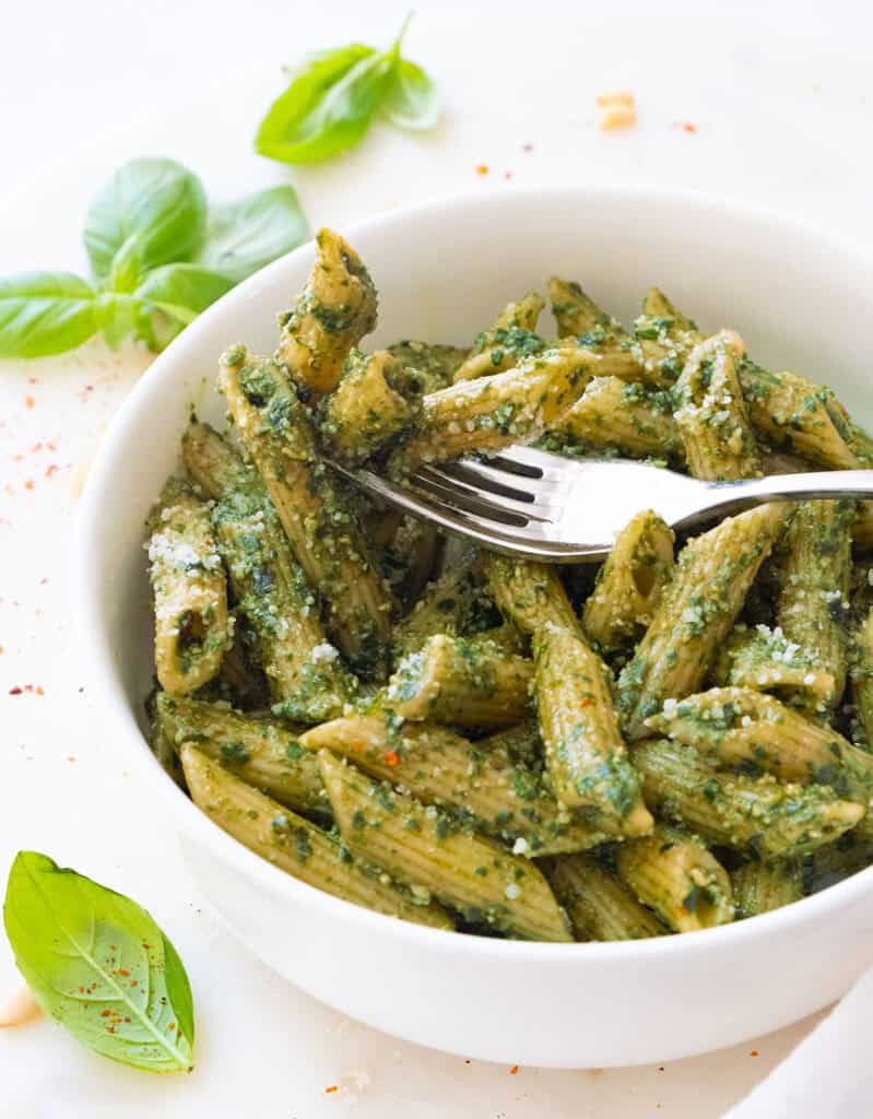 A fork with penne with pesto.