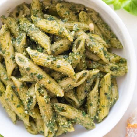 Penne with pesto in a white bowl.
