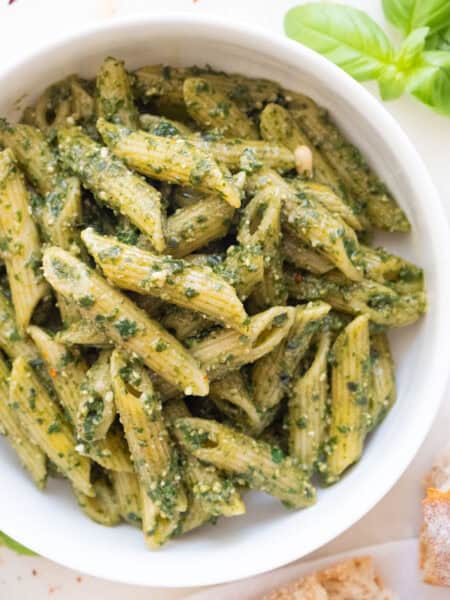 Penne with pesto in a white bowl.