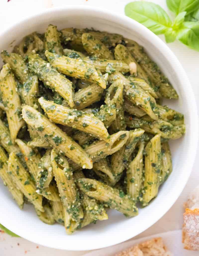 A white bowl with penne with pesto.