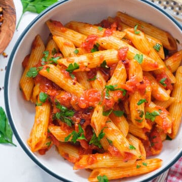 Top view of a white bowl full of penne arrabbiata.