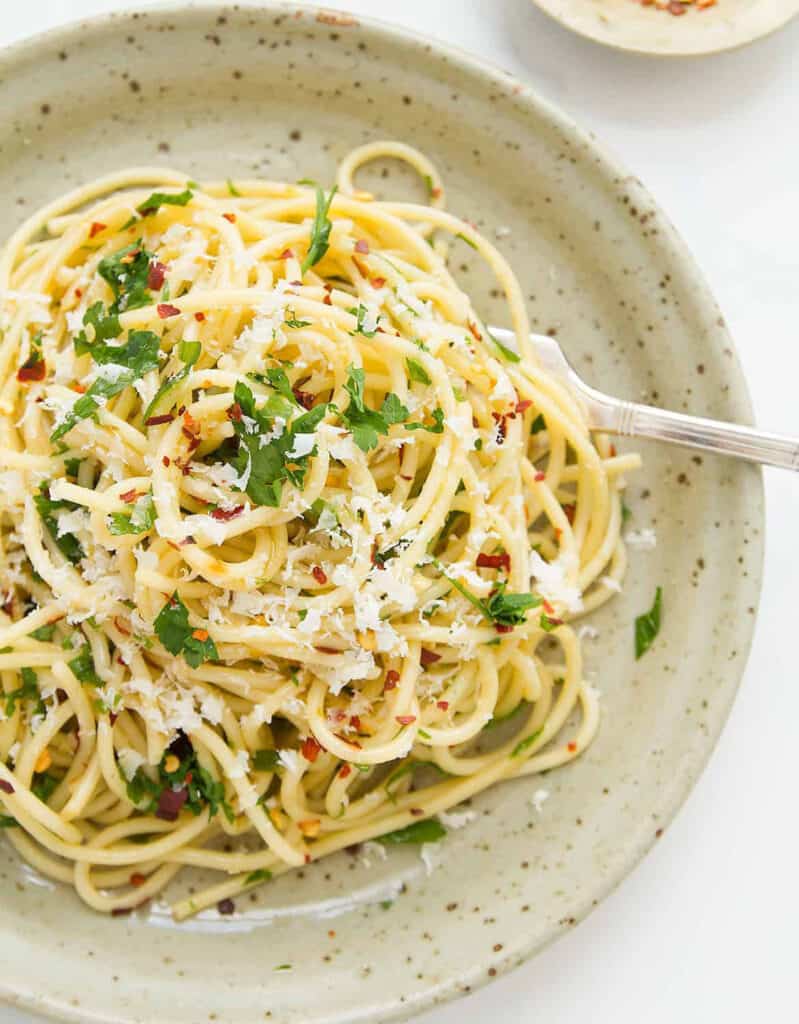 우리가 가장 좋아하는 이탈리아 파스타 요리법 중 하나인 파슬리를 곁들인 스파게티와 올리브 오일로 가득 찬 회색 접시의 최고 전망.