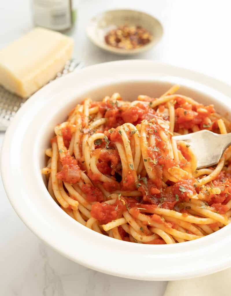 Close-up of a white bowl full of Italian marinara pasta.