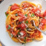 Top view of a white plate full of pasta napoletana.