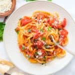 Top view of a plate full of spaghetti with canned tomato sauce.