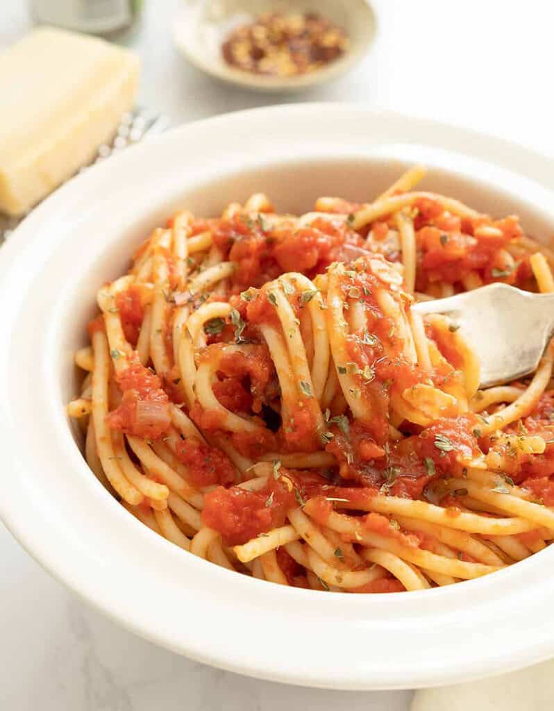 Close-up of a white bowl full of spaghetti marinara, of the popular italian recipes made with canned tomatoes.