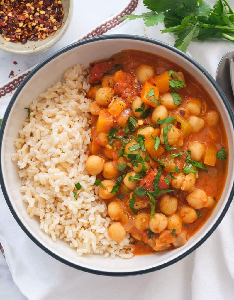 Top view of a white bowl full of rice and chickpea stew made using canned tomatoes.