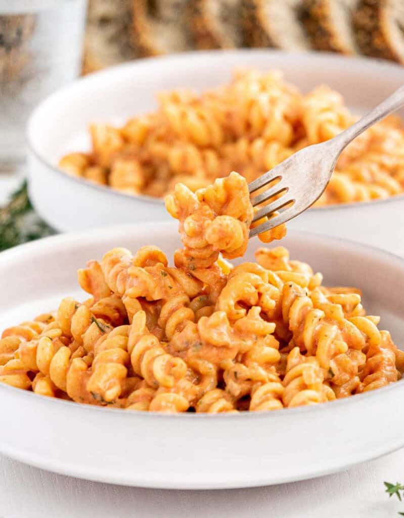 Two white bowls full of fusilli with creamy tomato sauce.