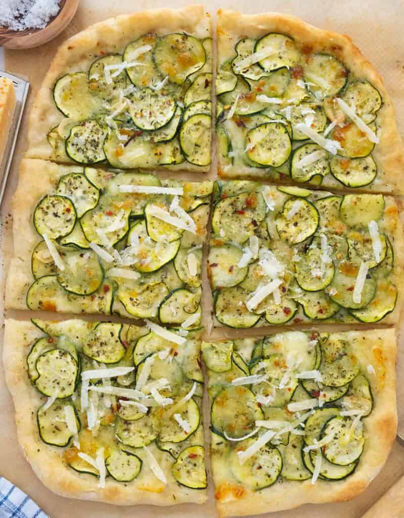 Top view of a large pizza with sliced zucchini and shaved parmesan.