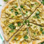 Top view of a round artichoke pizza cut into slices.