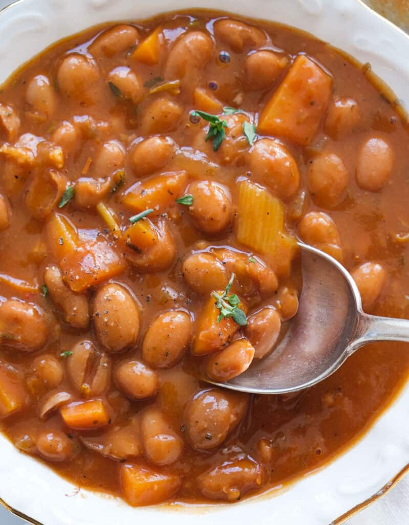 Top view of a white bowl full of creamy bean stew cooked in a red wine sauce.