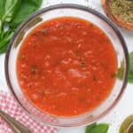 Top view of a glass bowl full of easy tomato sauce with fresh basil.